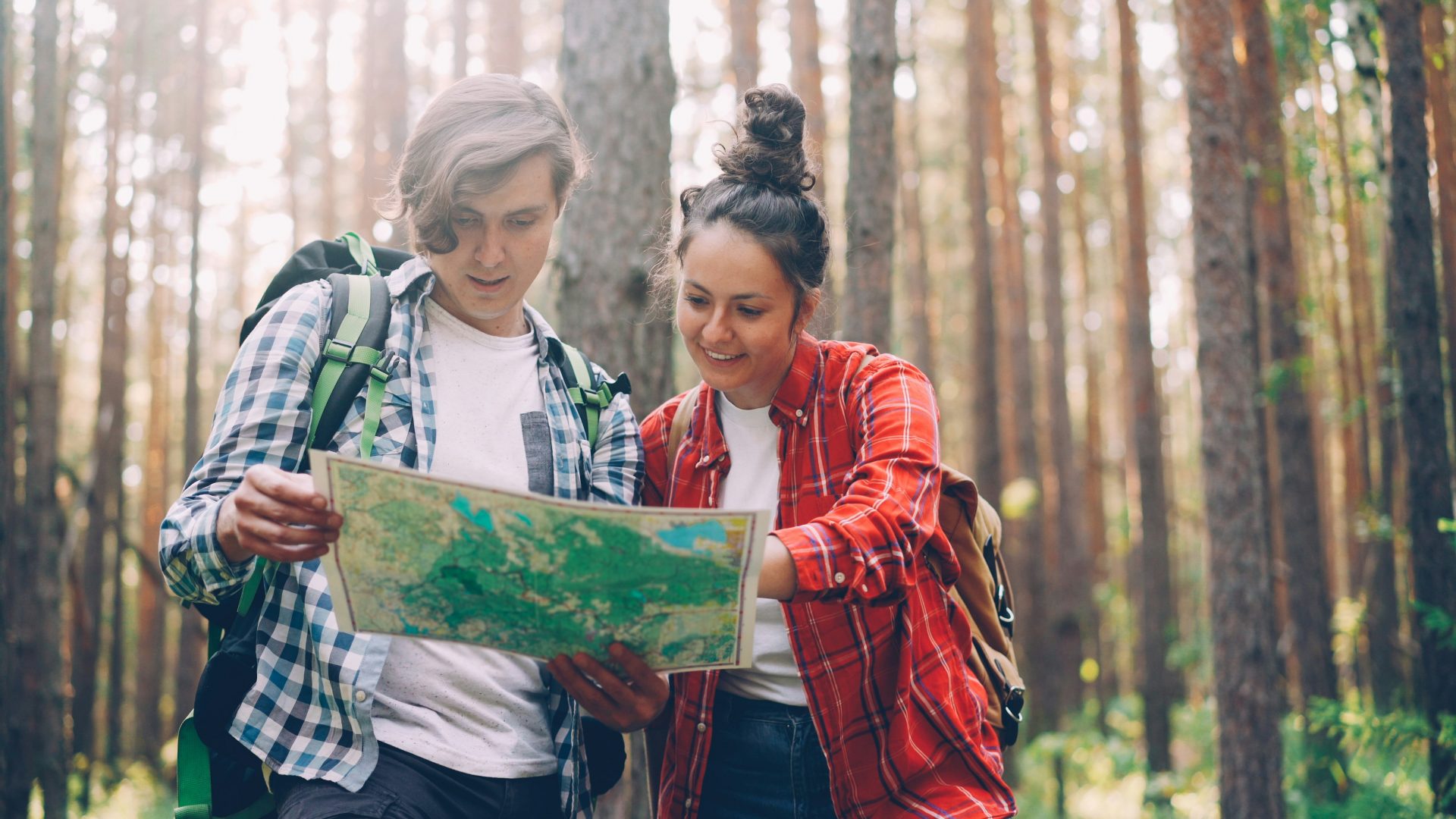 Two hikers looking at a map in a forest